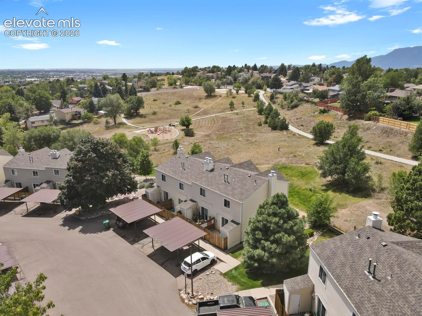 Townhome property featuring carports, an outdoor patio, and a landscaped yard