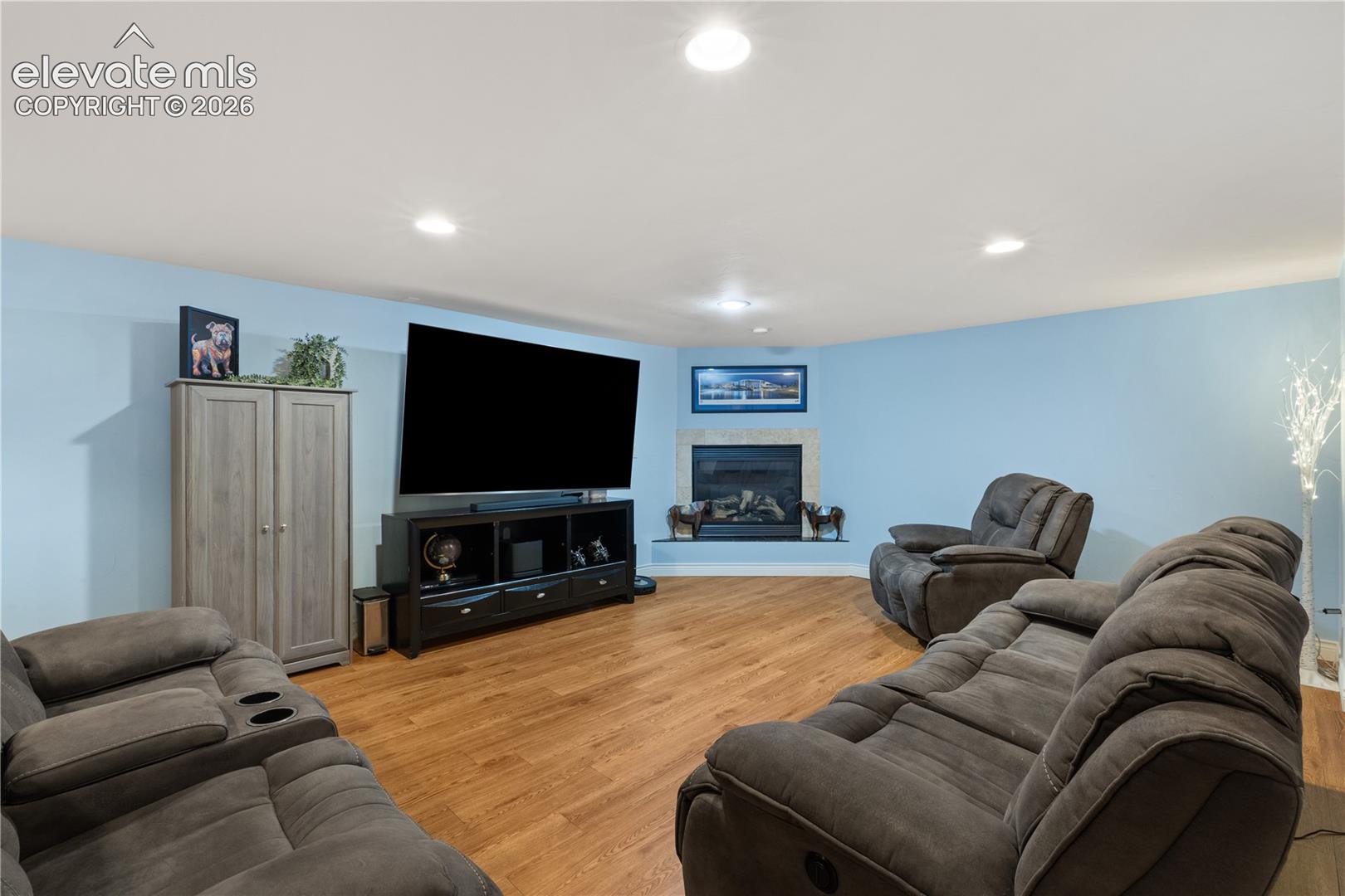 Spacious entertainment area featuring wood-finish flooring and light blue walls