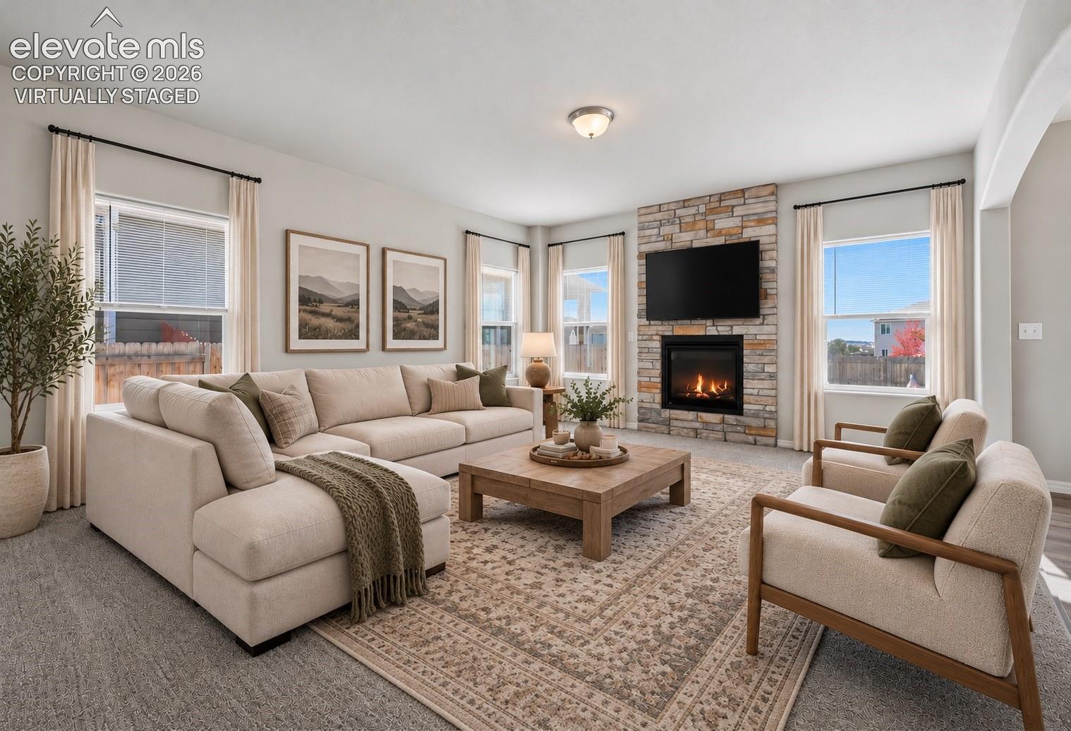Virtually staged living area featuring a floor-to-ceiling stone-veneer fireplace with a built-in mantle, neutral wall tones, and expansive windows