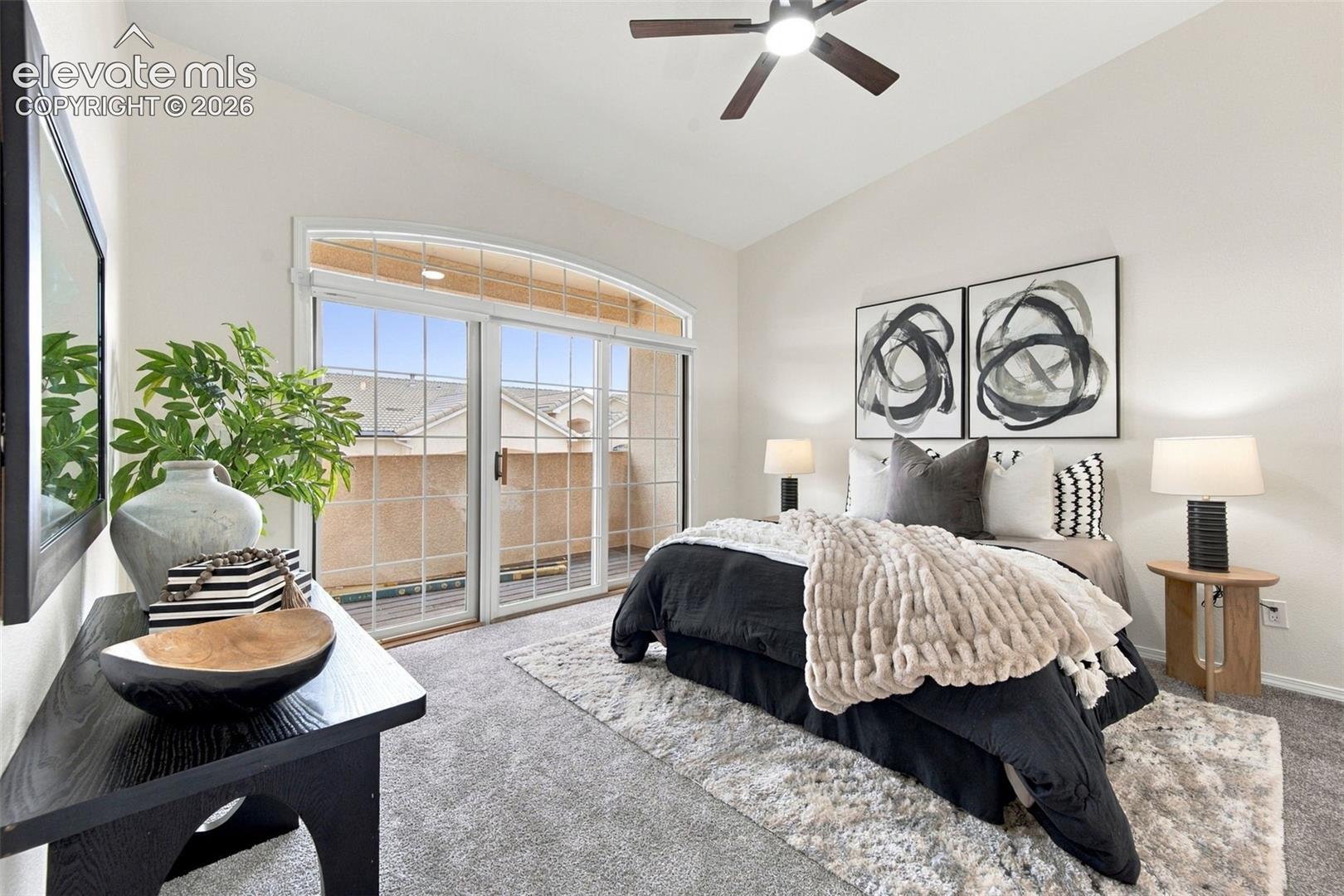 Neutral-tone wall finishes, wall-to-wall carpeting, ceiling fan with integrated lighting, and a large sliding glass door topped with a rounded transom window providing outdoor access