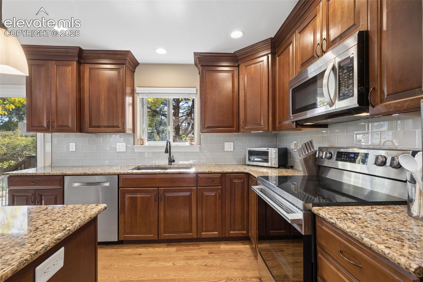 Updated kitchen with island, stainless steel appliances, granite counters and glass subway tile backsplash