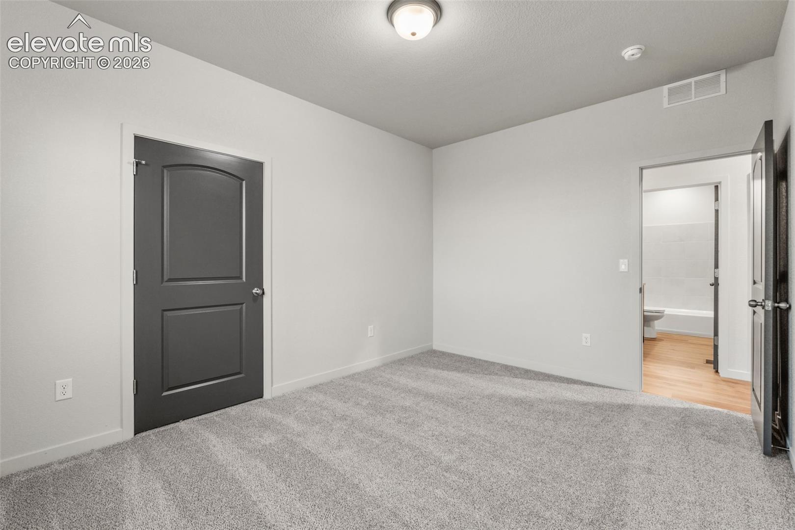 Neutral-toned wall paint, gray wall-to-wall carpeting, and dark-toned interior doors with brushed-nickel hardware