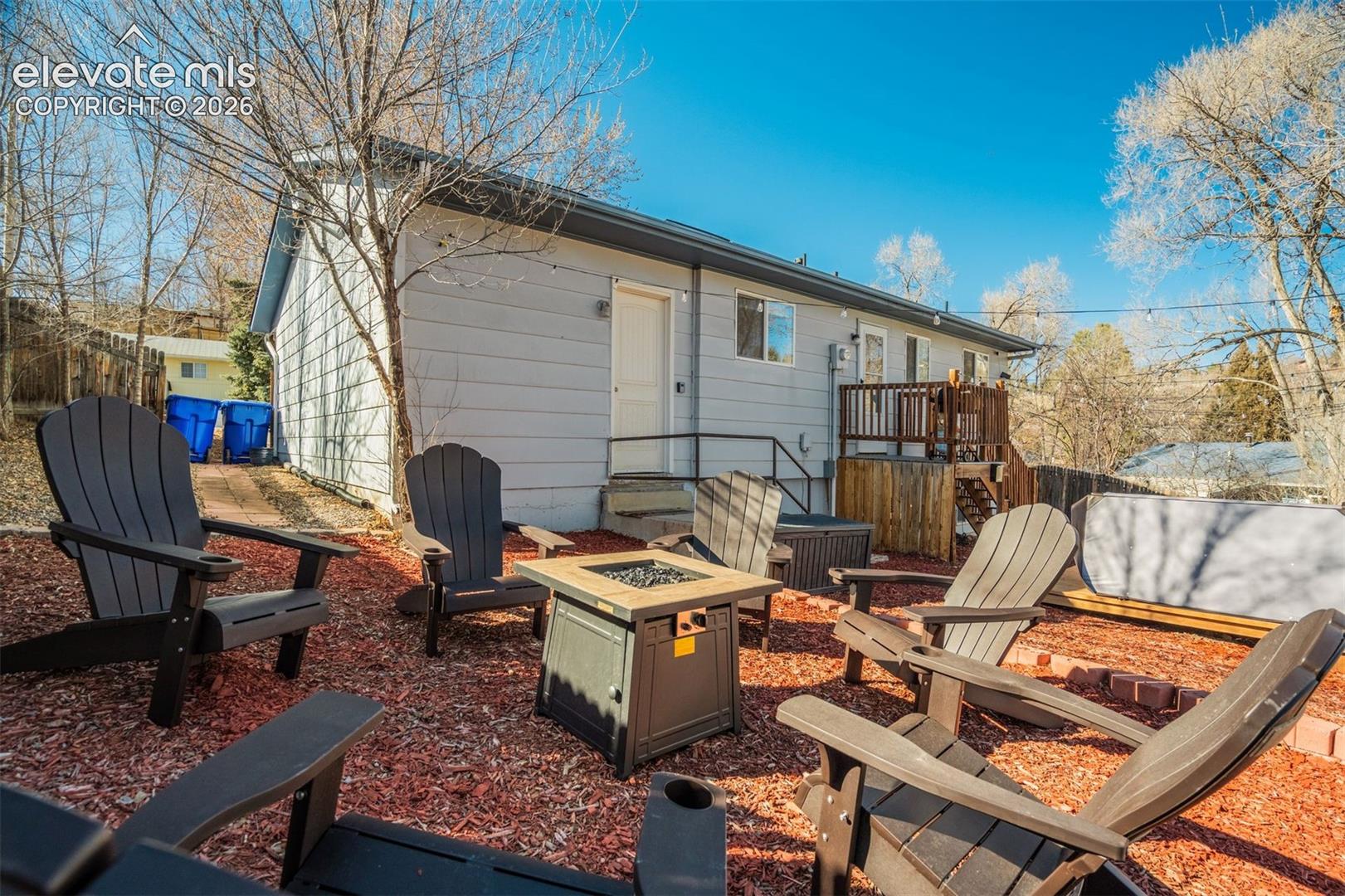 Rear exterior featuring light-colored siding, a multi-level wood deck, and a distinct outdoor entertainment area