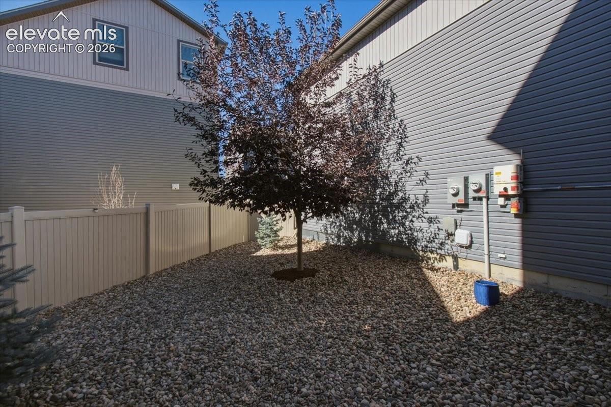 Gravel yard with a mature tree and a neutral-toned privacy fence