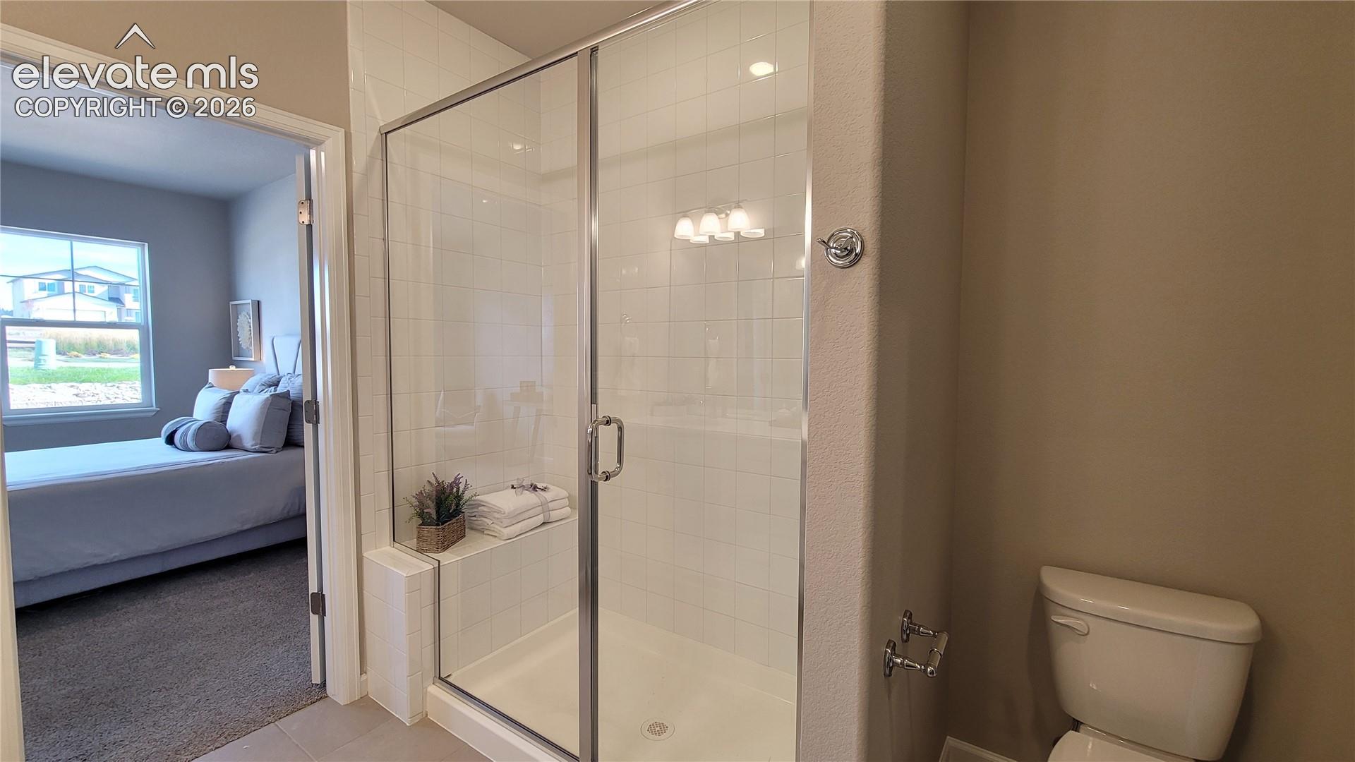 Primary 3/4 Bathroom with double vanities, shower with bench and tile surrounds, cabinet/drawer pulls, quartz countertop, and linen closet! 