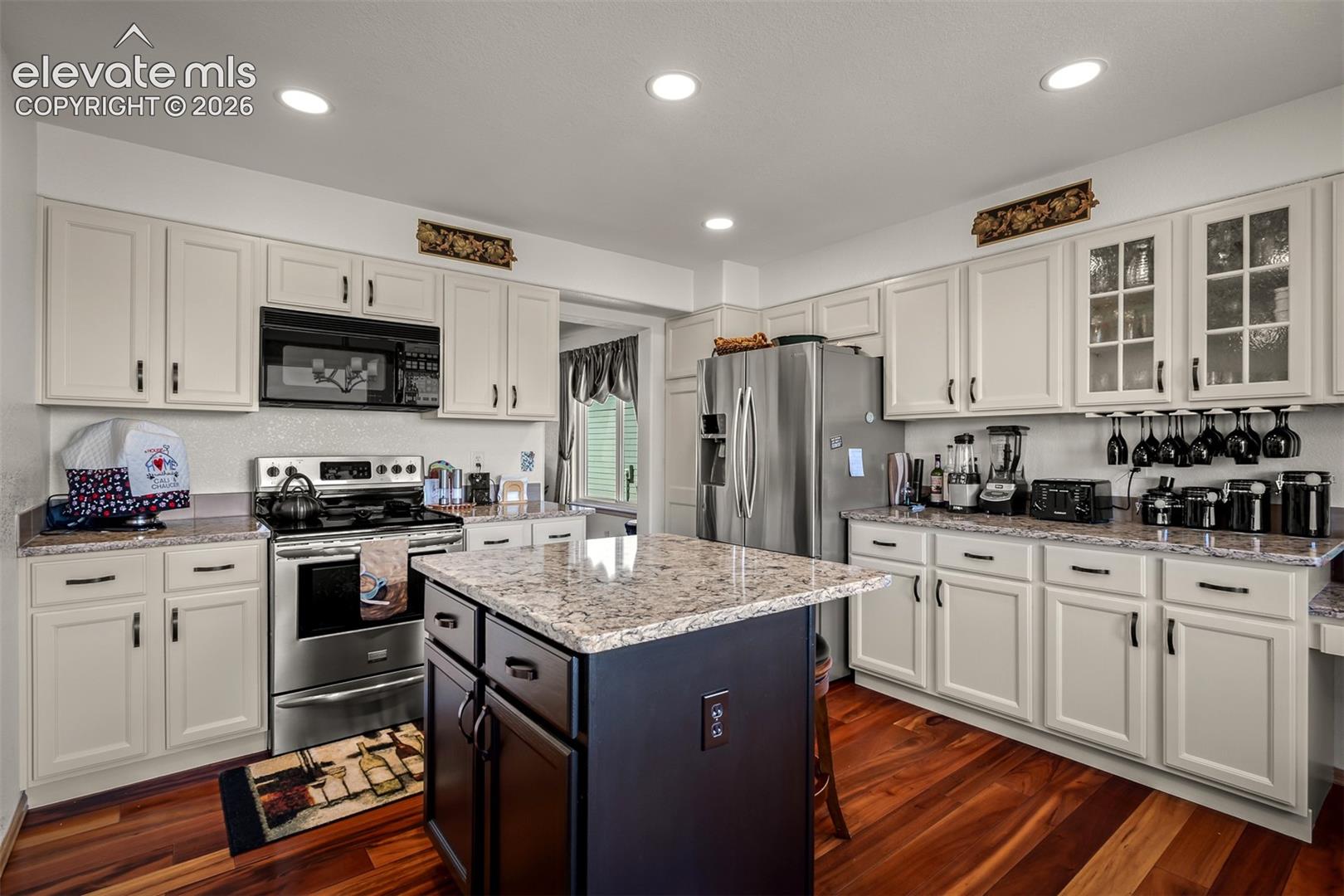 Kitchen featuring a central island with a quartz countertop, light-colored cabinetry, stainless steel appliances, recessed lighting, and Brazilian Koa Hardwood flooring.
