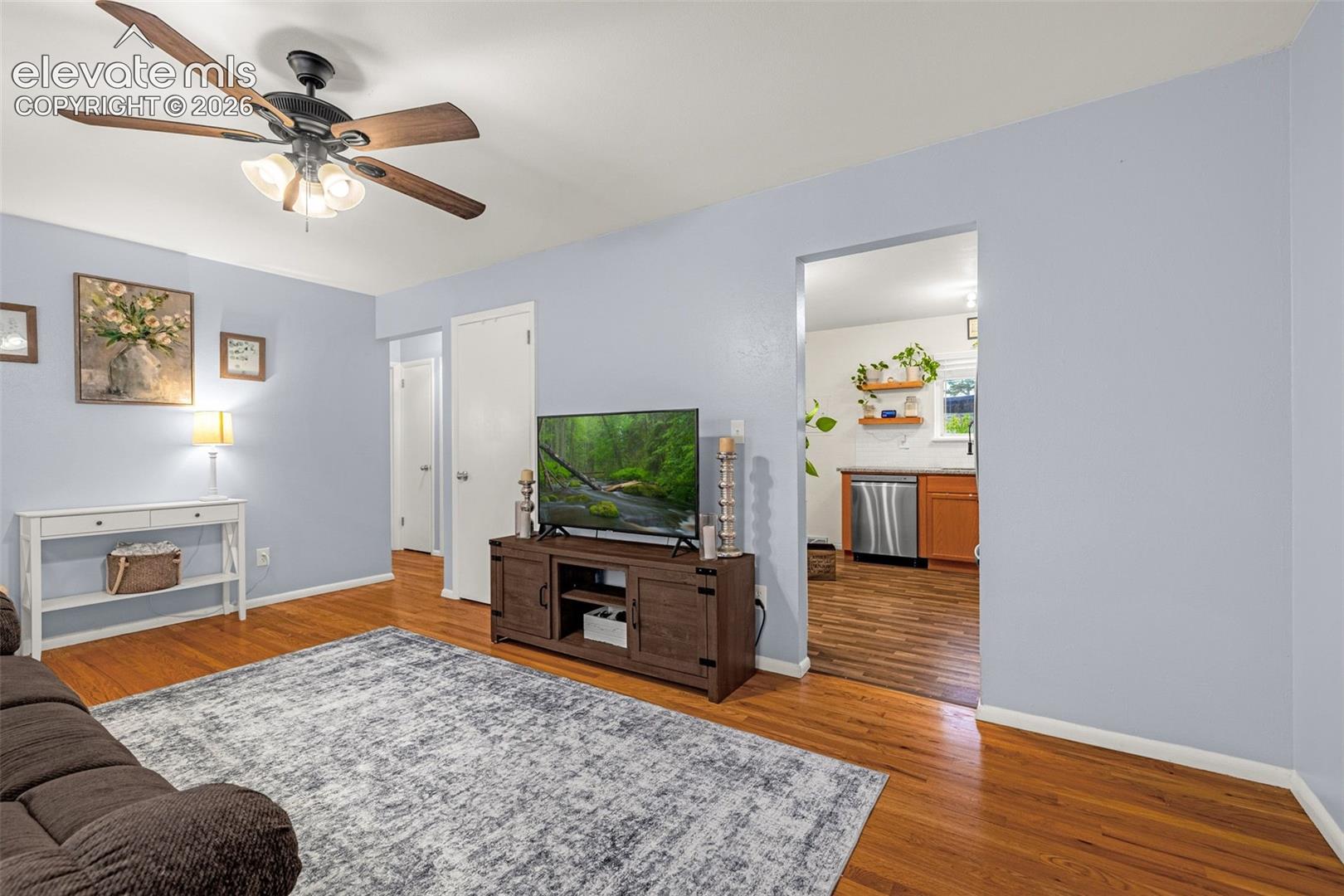 Hardwood flooring, painted walls, ceiling fan with integrated lighting, and white interior doors