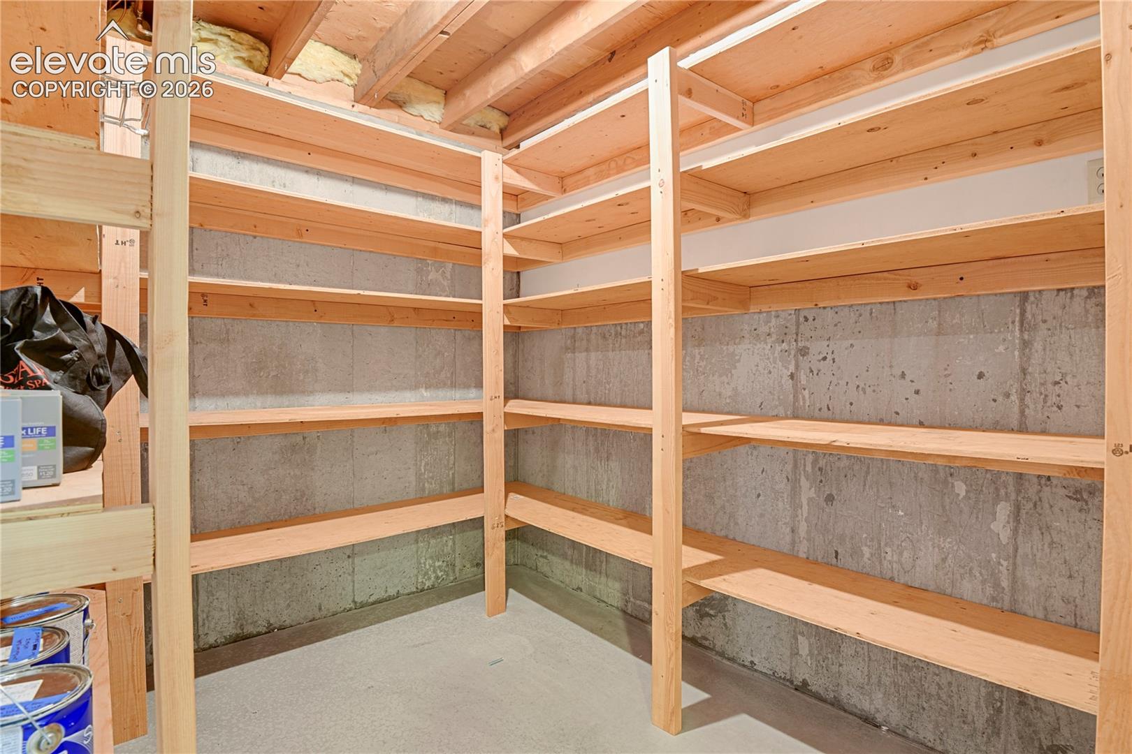 Built-in wood shelving units featuring multi-level storage, concrete walls, and exposed ceiling joists