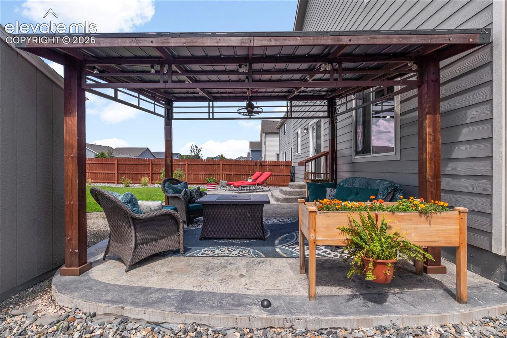 Outdoor patio with a wood-framed pergola, stamped concrete base, and integrated overhead lighting