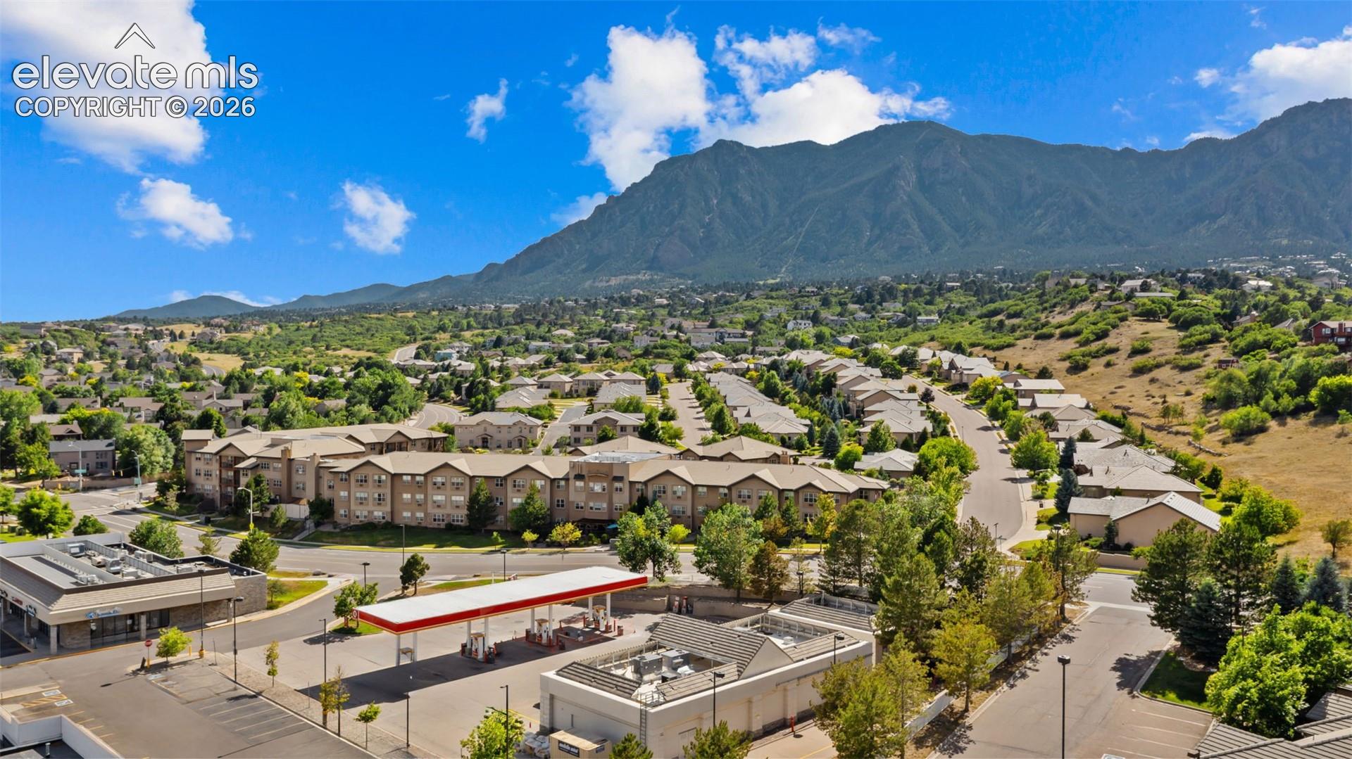 Expansive mountain scenery framing a residential community with mature trees and a clear blue sky