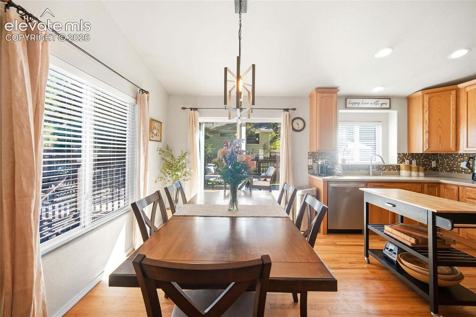 Wood-finish flooring throughout, with a dining area featuring a linear chandelier and sliding glass door