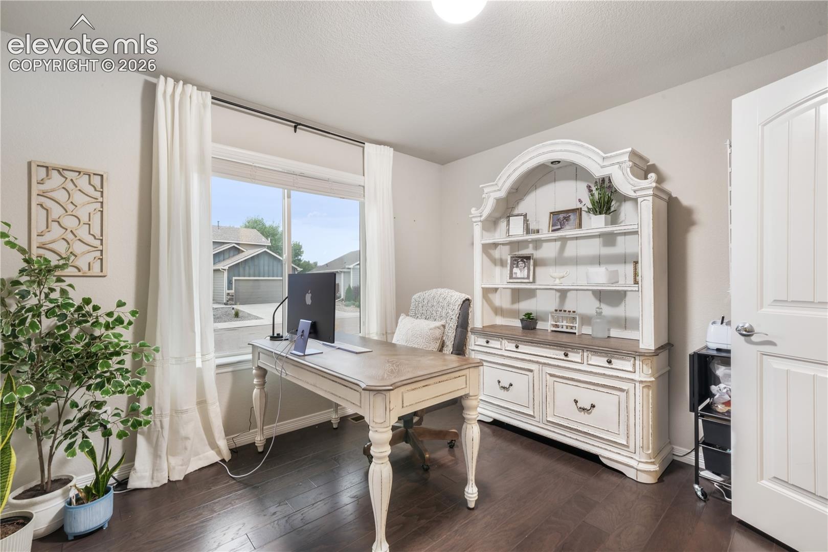 Hardwood-style flooring, white trim, and a large window with natural light