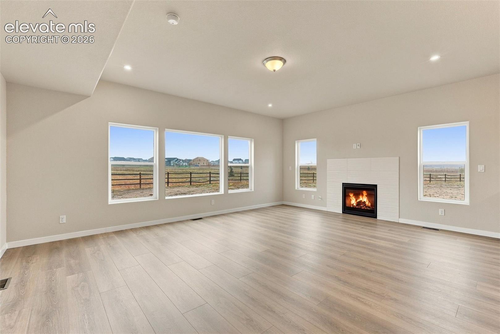 Open-concept space featuring wood-finish flooring, multi-pane windows, and a tiled fireplace surround