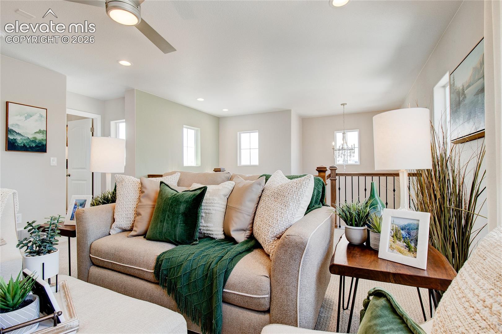 Open floor plan featuring recessed lighting, a modern ceiling fan, balanced neutral wall tones, and a wooden staircase railing with vertical balusters