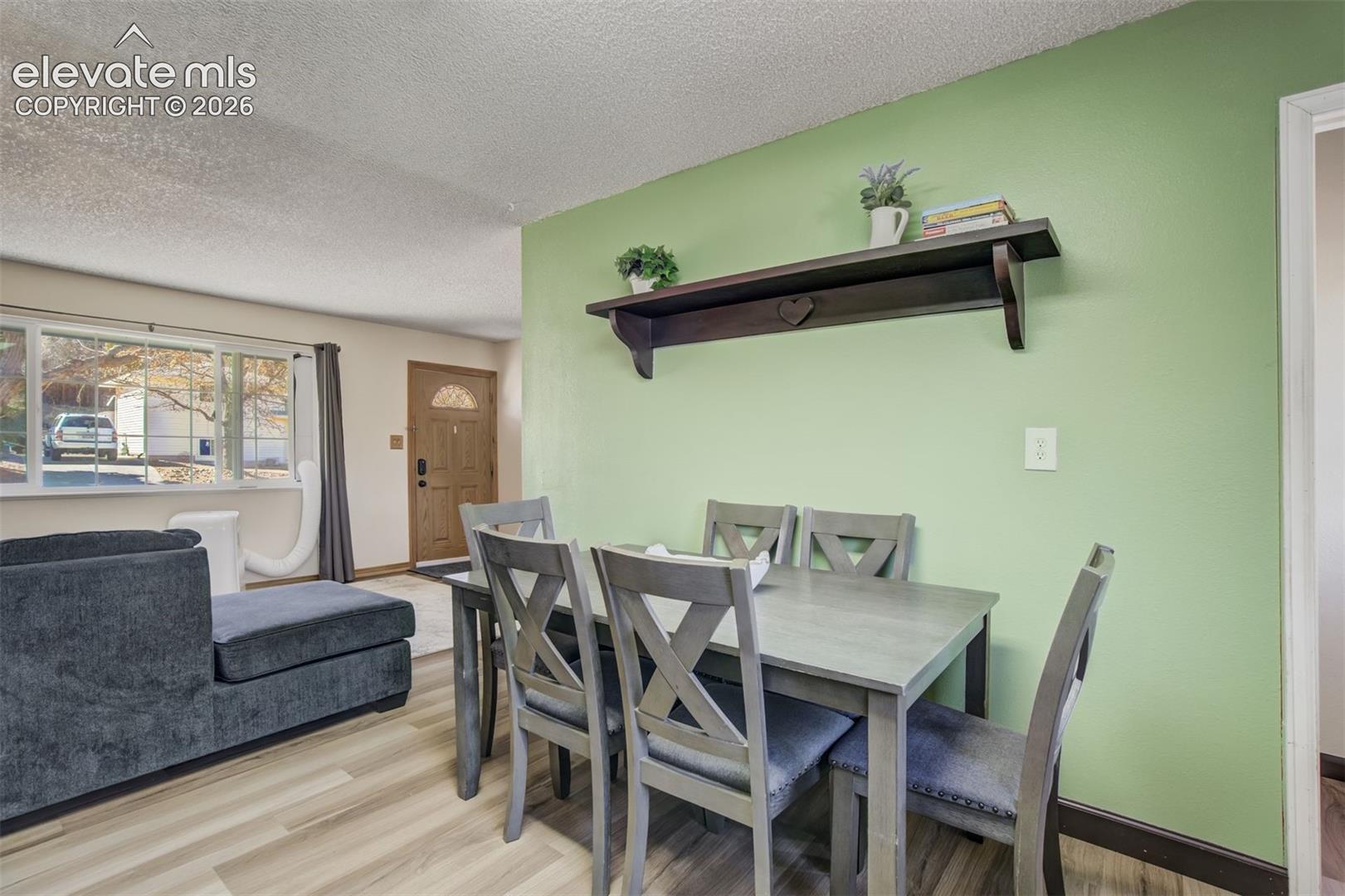 Wood-finish flooring throughout, light green accent wall, and a large front window