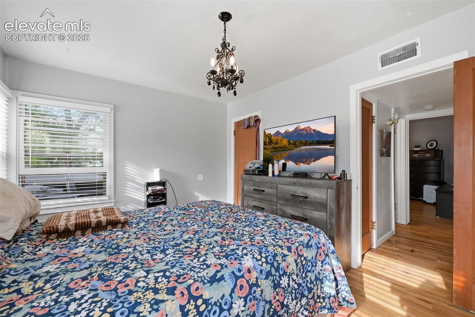 Hardwood flooring, architectural chandelier, and a window with blinds