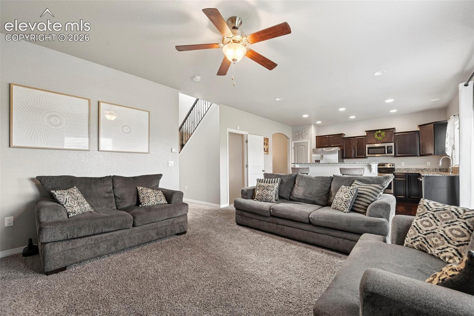 Open-concept living area featuring carpeted flooring and an overhead ceiling fan