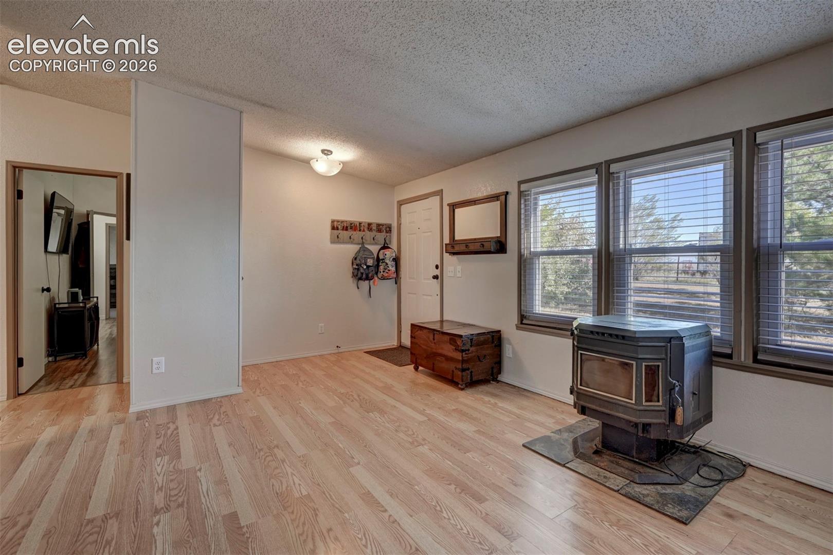 Entrance foyer with a wood stove, a textured ceiling, and light wood-style flooring