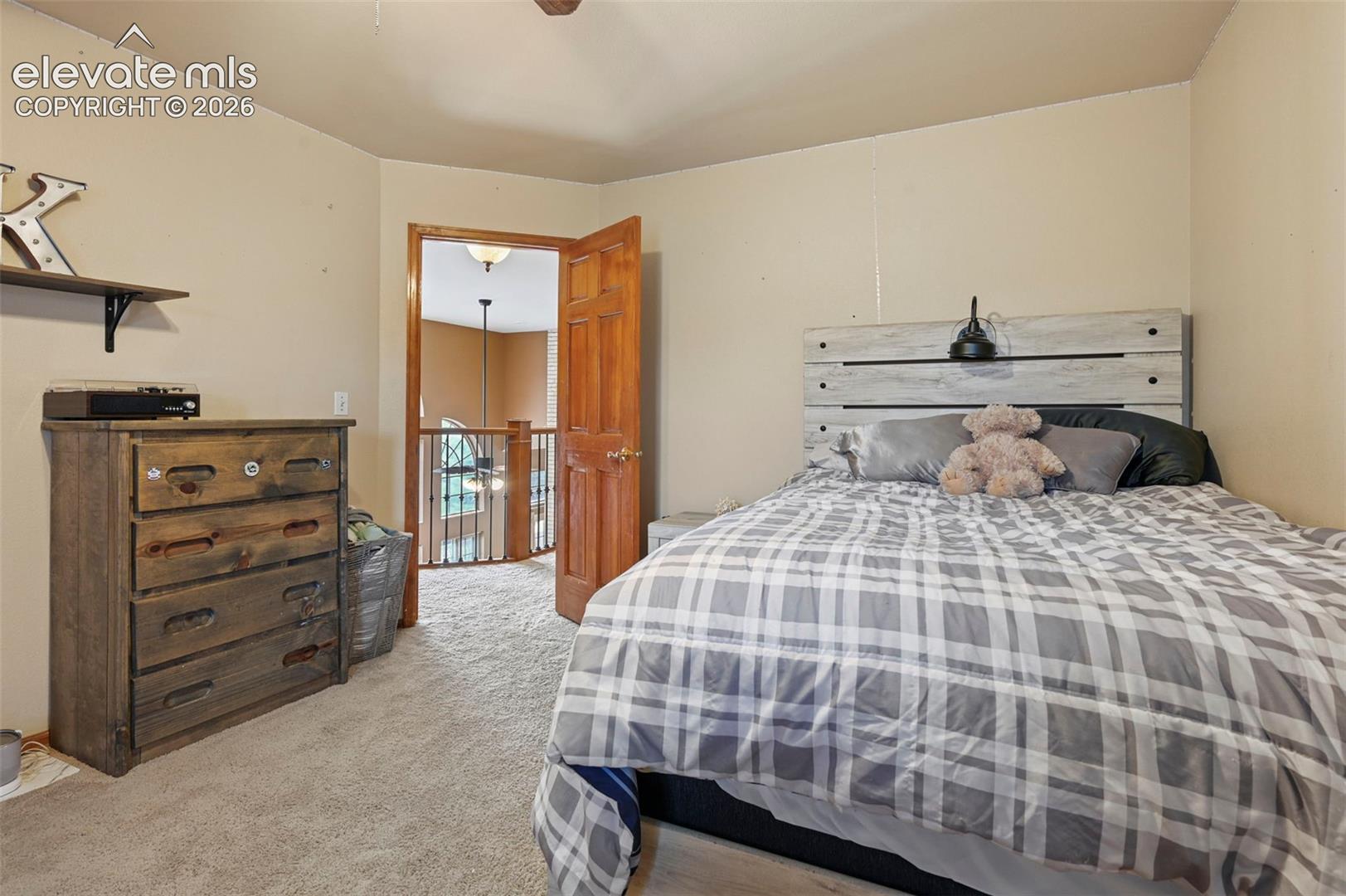 Second floor bedroom with carpeted flooring, wood-finish door, and light-toned wall paint