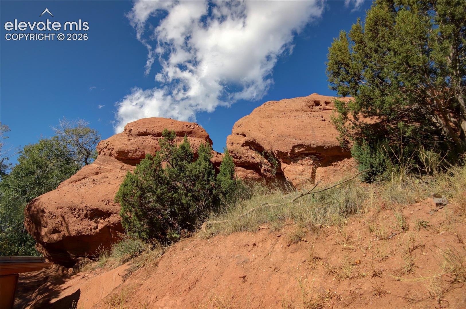 Natural sandstone rock formations set against native evergreen vegetation and rugged terrain