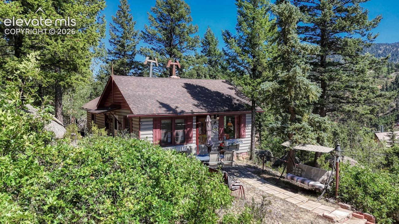 RARE OPPORTUNITY! Welcome to Deer Path, a truly one-of-a-kind mountain retreat nestled in the heart of Green Mountain Falls. Built in 1930 and lovingly passed down through the original family, this remarkable 2 bedroom, 1 bath cabin offers a rare chance to own an authentic piece of Colorado history. Rich original wood paneling throughout, period-correct cork flooring, handcrafted cabinetry, and a custom rock fireplace showcase the timeless craftsmanship and character that simply can’t be recreated. Every room tells a story while preserving the warmth and charm of its original design. Just outside the cabin an area was flattened to accommodate 3+ cars and provides ample parking without taking away from the views!Unlike many cabins in the area, Deer Path enjoys expansive views, exceptional privacy, and nearly a full acre of highly desirable land—creating a peaceful mountain setting with endless possibilities. The property is being offered fully furnished, including antique furniture and carefully preserved pieces dating back to the 1930s, allowing the next owner to step into a home that has remained virtually untouched through generations. Whether you’re searching for a private mountain getaway, a legacy property to keep in the family, or a truly unique Colorado cabin, Deer Path is a once-in-a-generation opportunity to own an irreplaceable piece of Green Mountain Falls history.