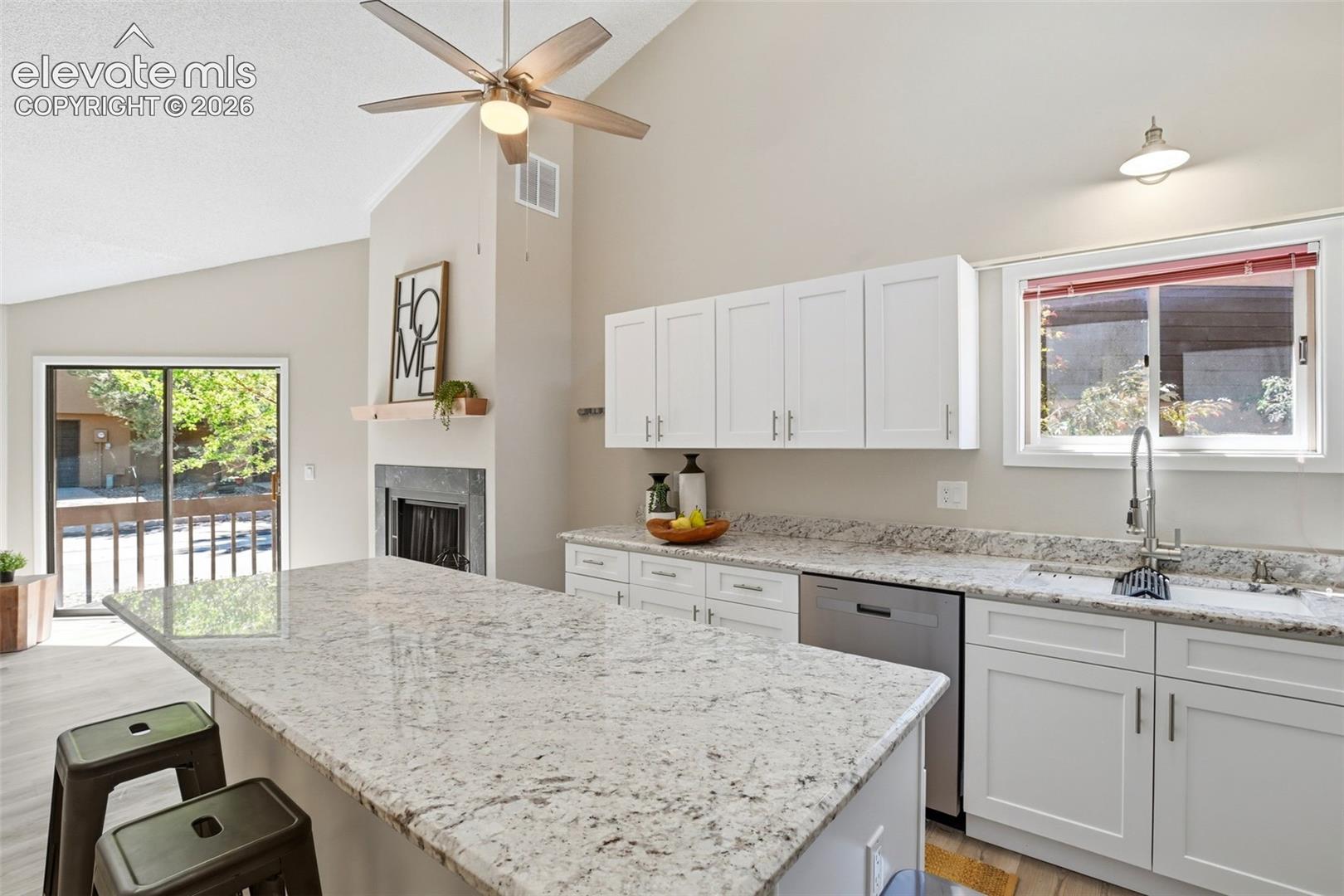 Kitchen featuring a large island with stone countertops, white shaker cabinetry, and stainless steel appliances