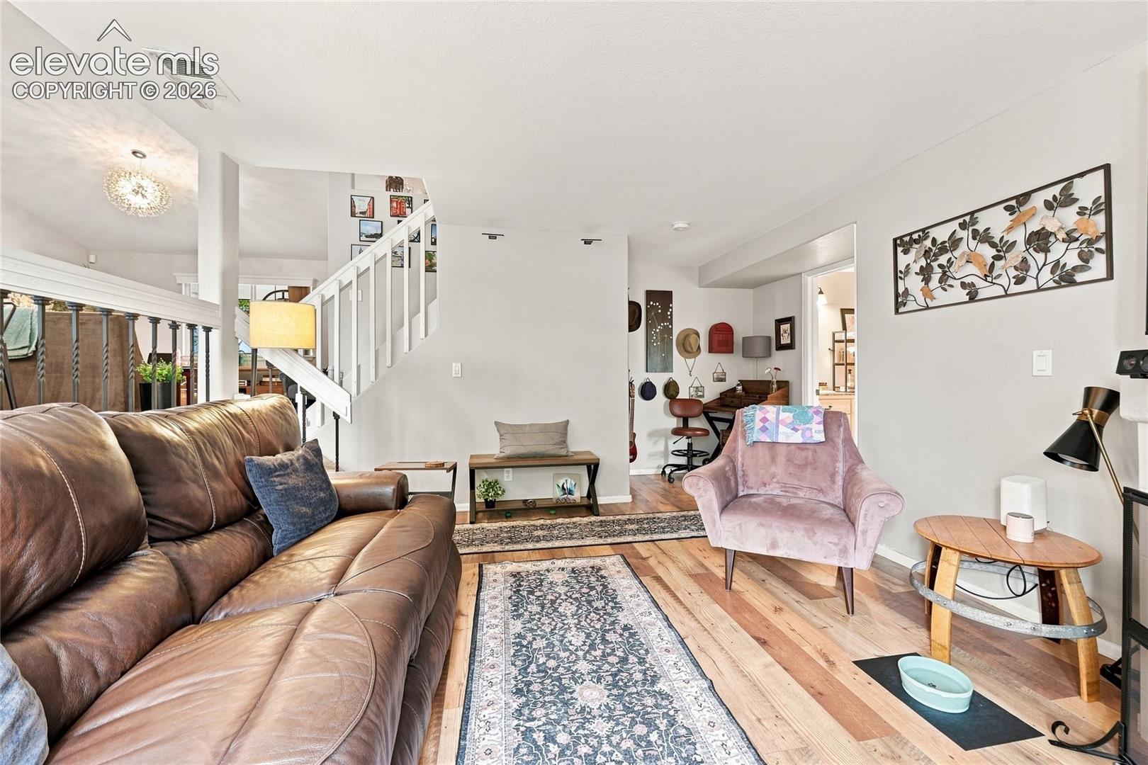 Open-concept room featuring wood-finish flooring, a white wooden stair railing with spindle balusters, and recessed ceiling lighting