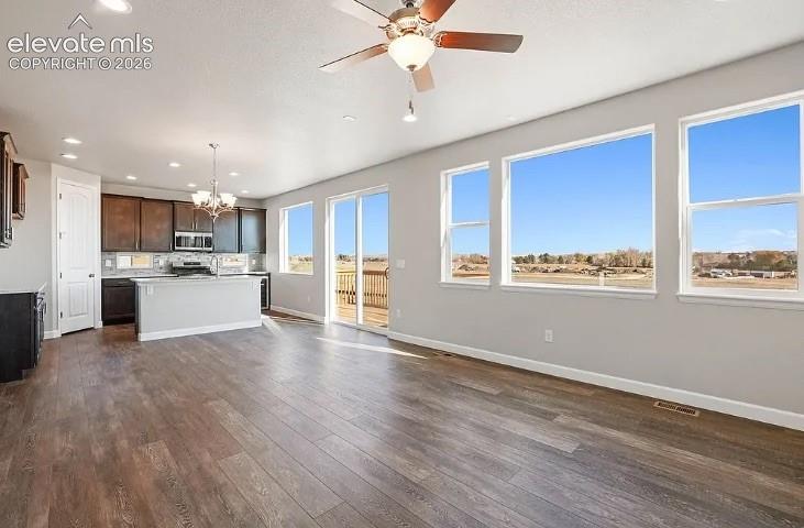 Open-concept kitchen featuring dark cabinetry, a central island, wood-finish flooring, recessed lighting, and large windows