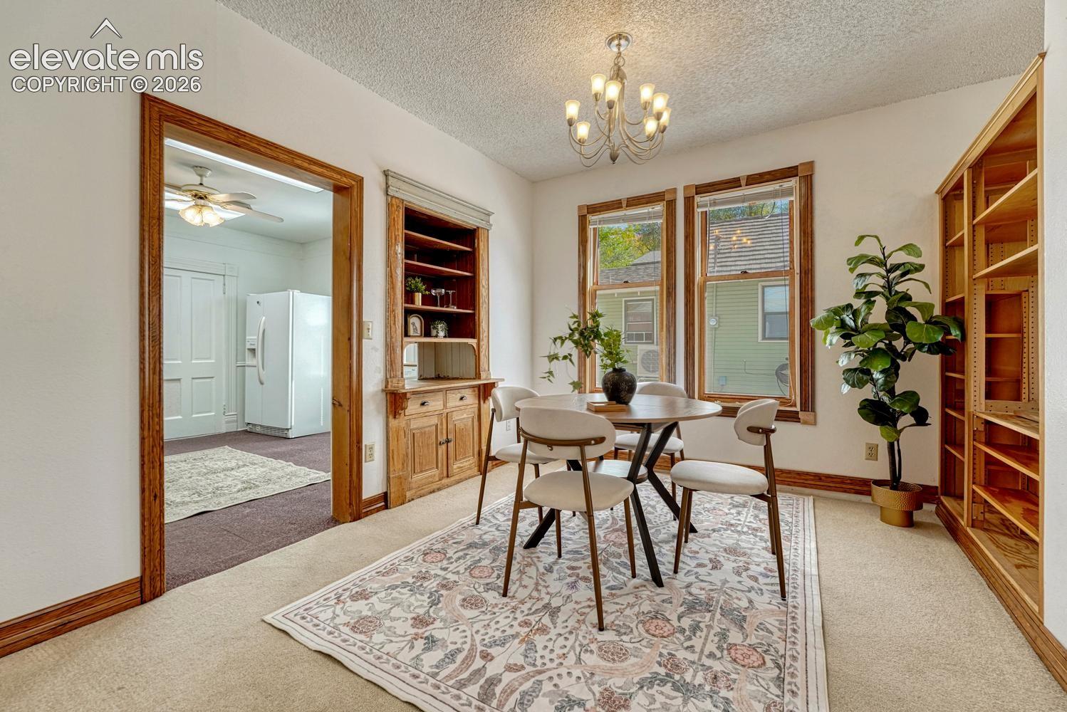 Recessed built-in cabinetry, wood-finish trim and doors, three large windows, built-in shelving, and a decorative chandelier