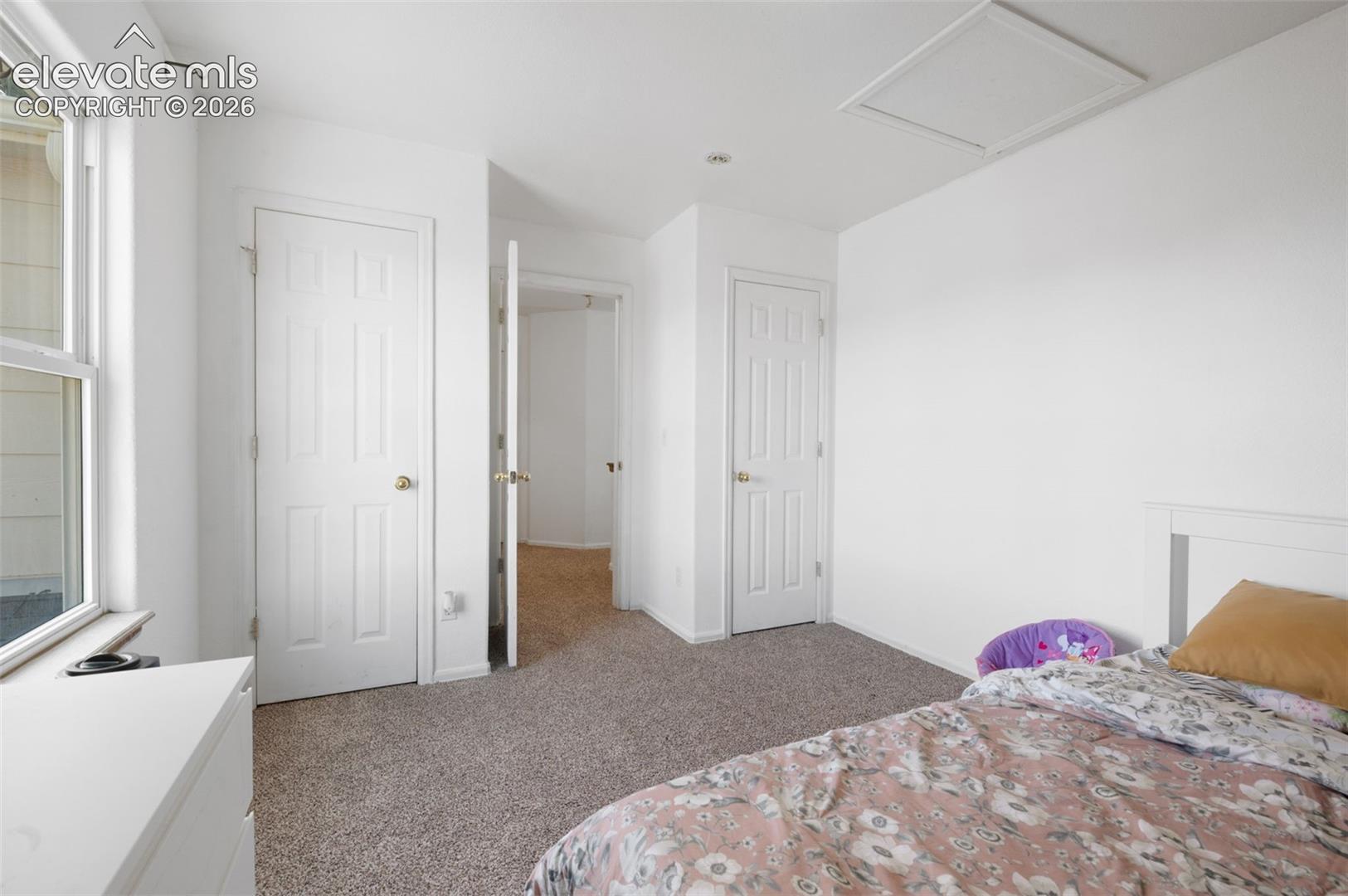 Carpeted room with a double-pane window, white trim, and a white six-panel door with a brass-finish knob