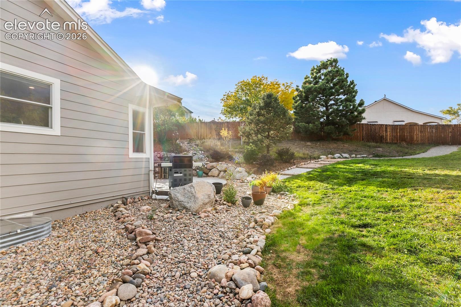 Expansive backyard featuring a manicured lawn, established landscaping, and a privacy fence