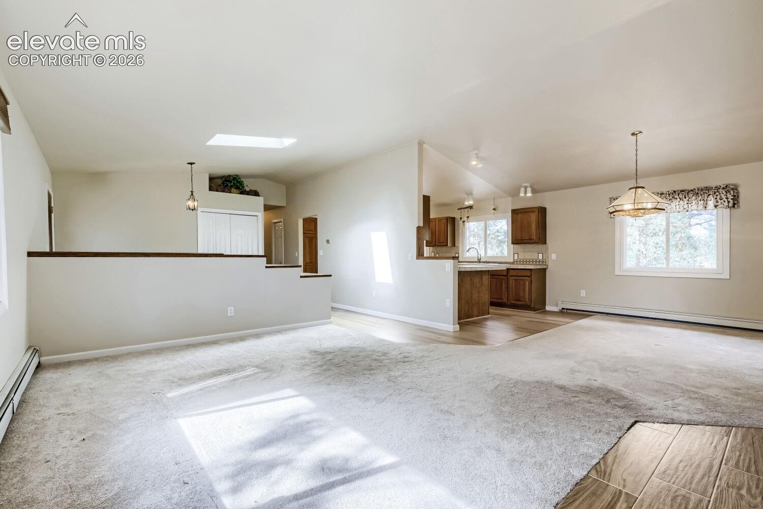 Open-concept living area featuring a skylight, pendant lighting, and a partial wall separating spaces