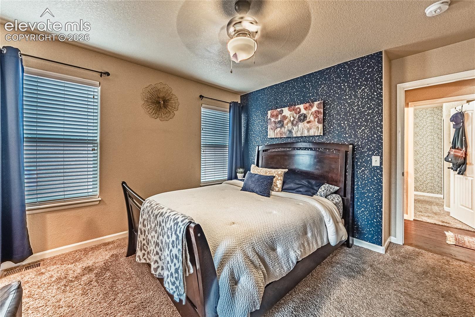 Carpeted bedroom with a textured ceiling, a ceiling fan, and wallpapered walls