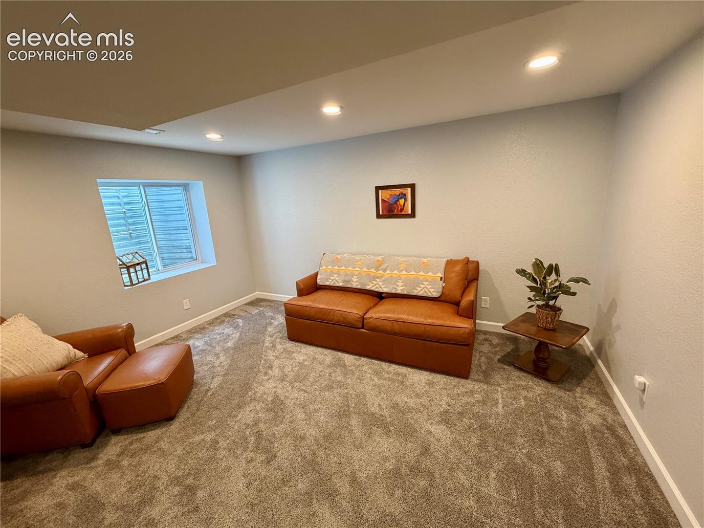 Carpeted basement room featuring recessed lighting, a window with horizontal blinds, and white baseboards