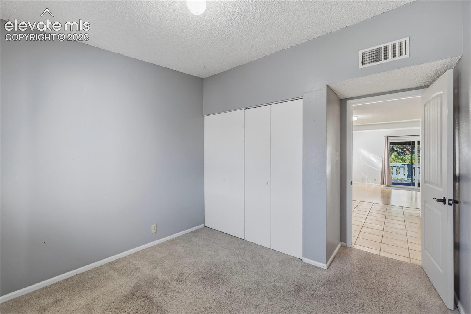 Neutral-toned interior featuring grey-painted walls, plush neutral carpeting, and a double-door closet