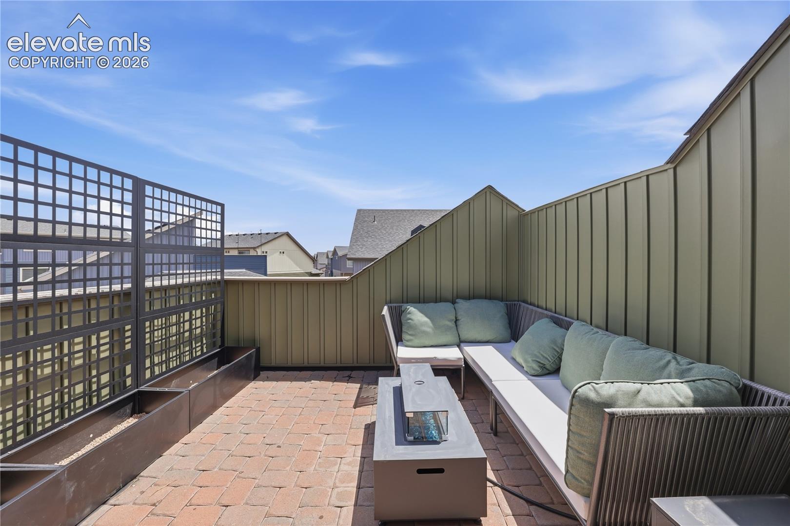 Rooftop patio featuring brick paver flooring, a linear planter system, and a decorative privacy screen
