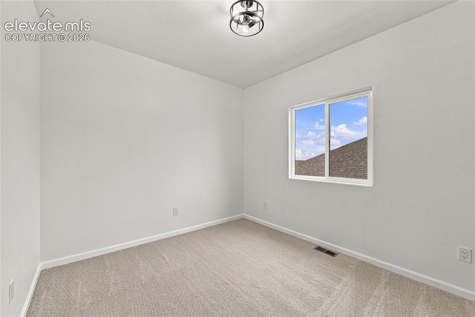 Neutral interior featuring wall-to-wall carpeting, a single-pane sliding window, and a contemporary semi-flush mount light fixture