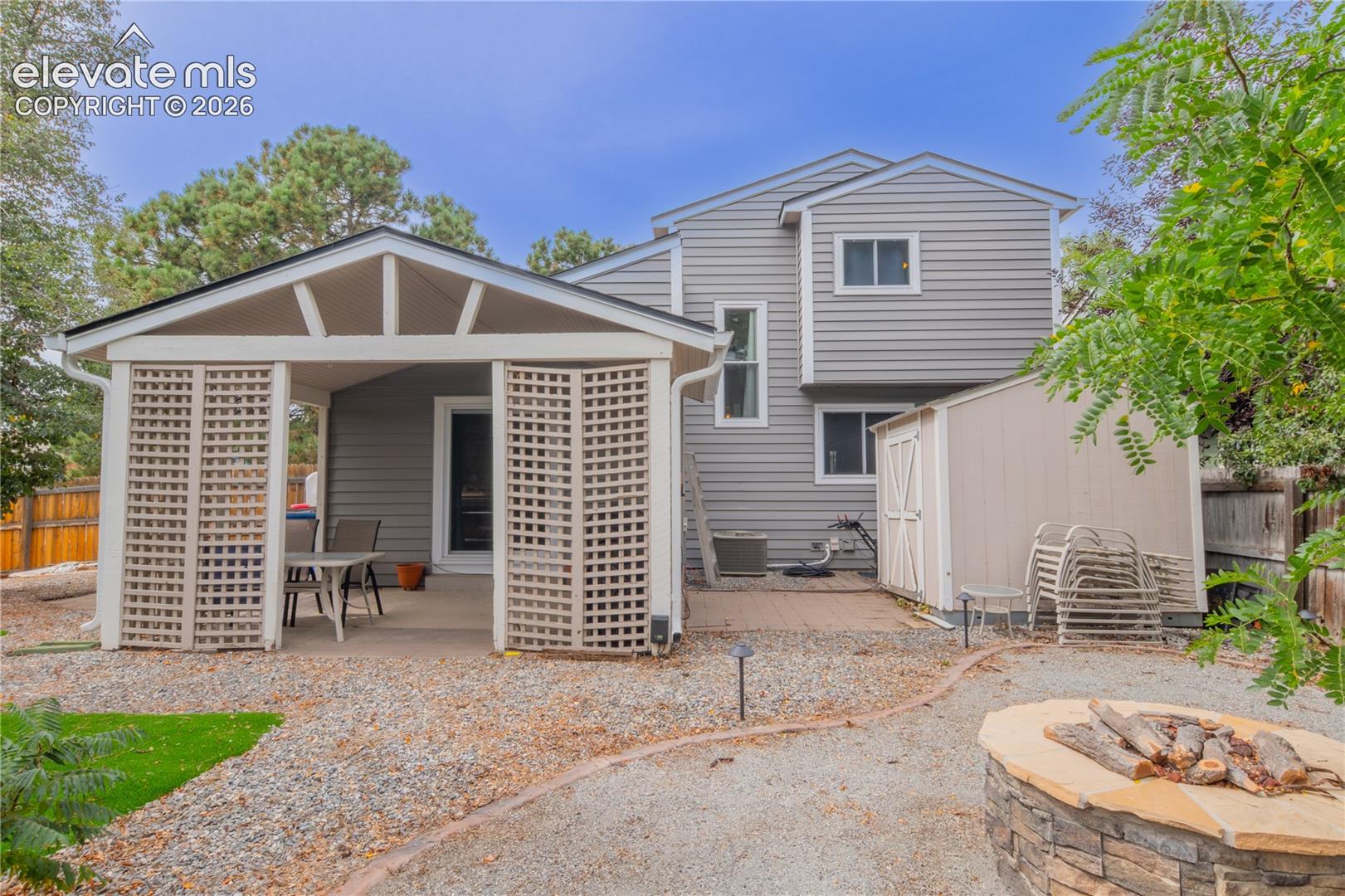 Private patio with lattice privacy screens, gravel ground cover, and a stone fire pit