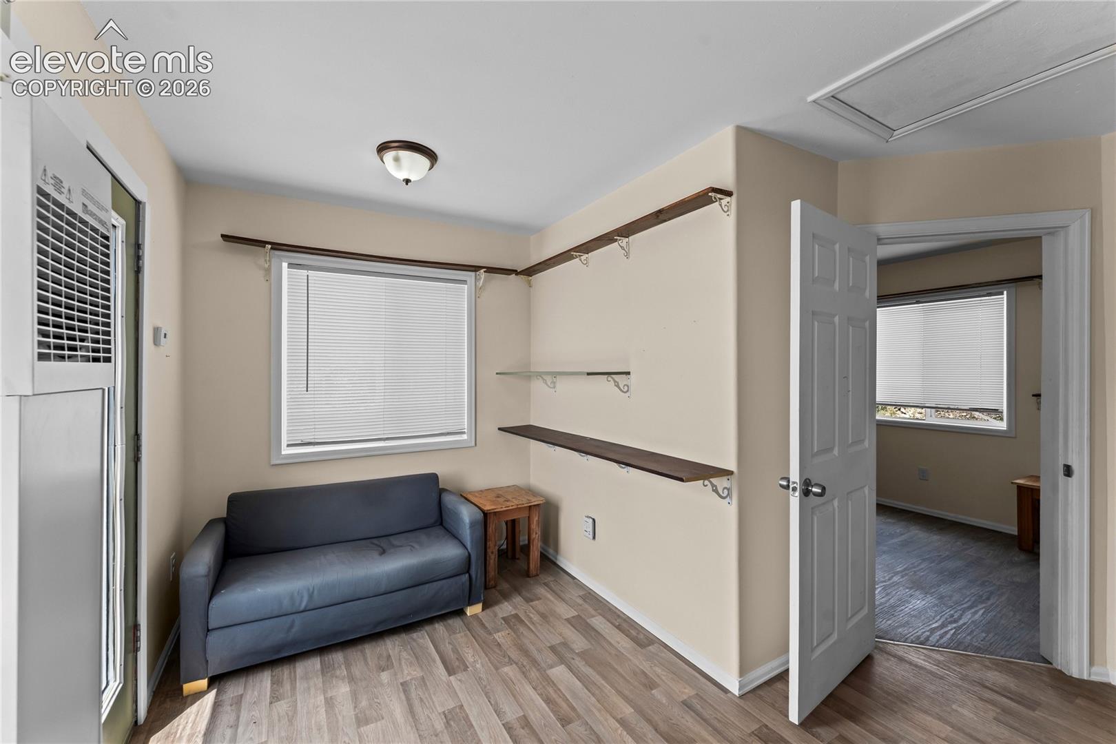 Versatile room featuring wood-finish flooring, neutral paint, and built-in shelving
