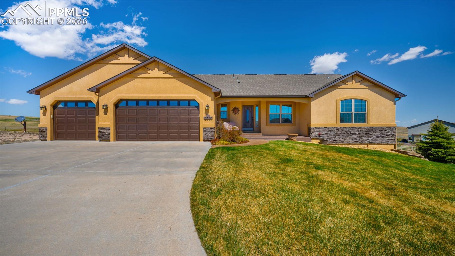 View of front of property featuring stucco siding, stone accent, a 3 car garage, covered porch, and driveway