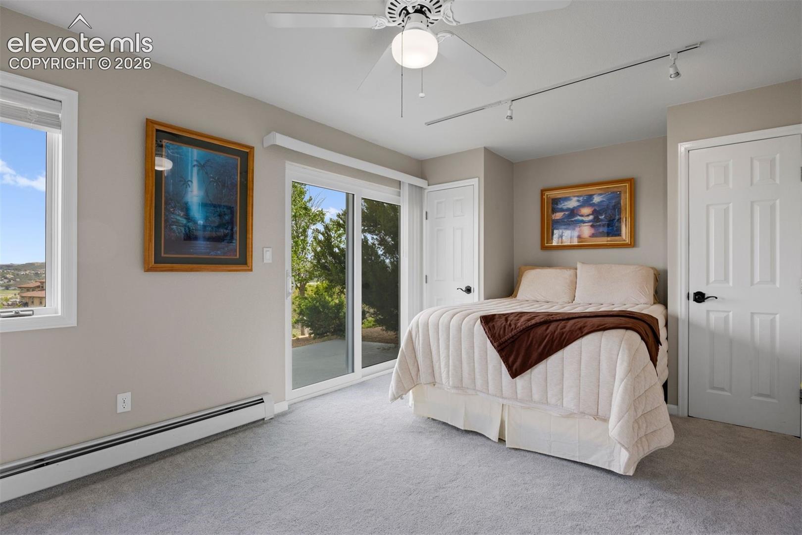 Main level bedroom with brand-new patio door, walk-out to private patio, and east-facing windows overlooking Castle Rock.