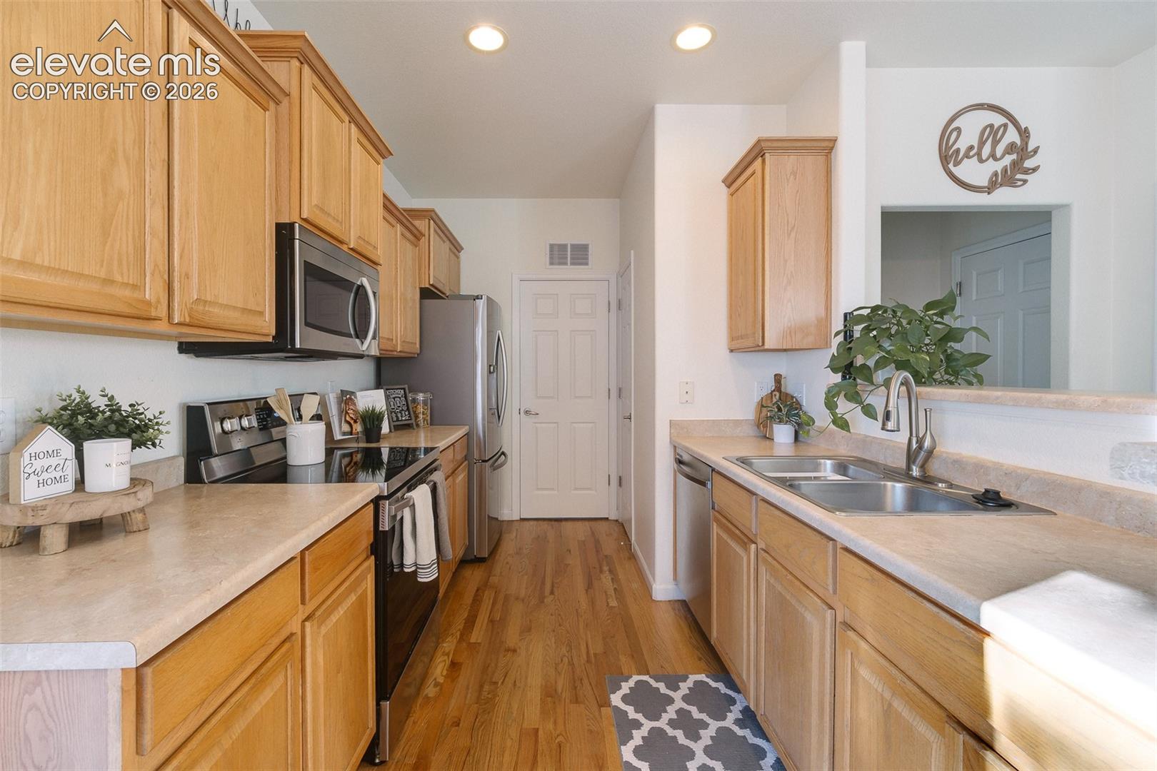 Kitchen featuring light wood cabinetry, light-toned countertops, stainless steel appliances, and wood-finish flooring