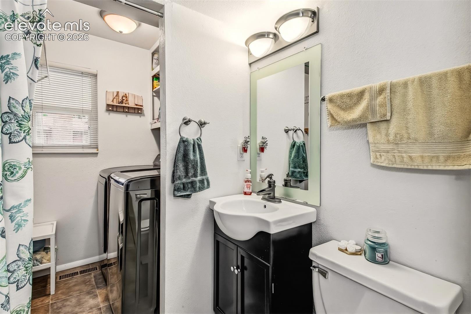Bathroom featuring a dark wood-finish vanity with a white basin, rectangular wall-mounted mirror, dual-light fixture, and built-in shelving