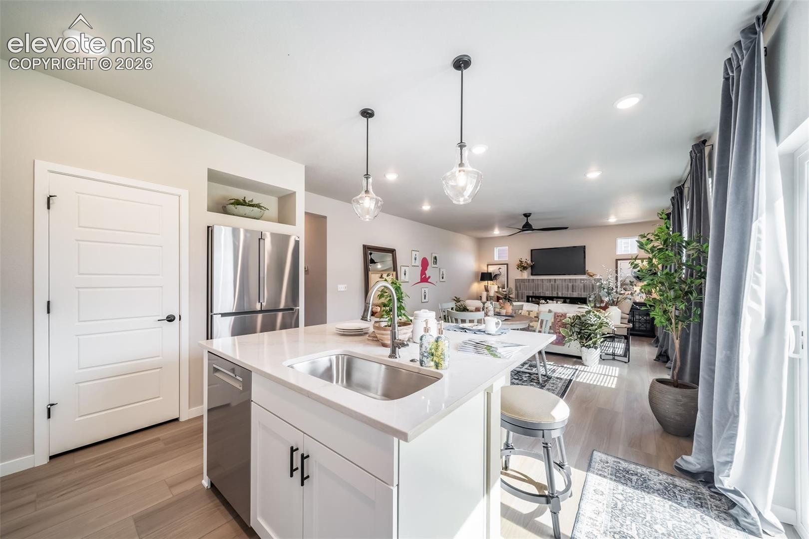 Kitchen island featuring a stainless steel sink, white countertop, white cabinetry with black hardware, and an integrated dishwasher
*Photos of a model home*