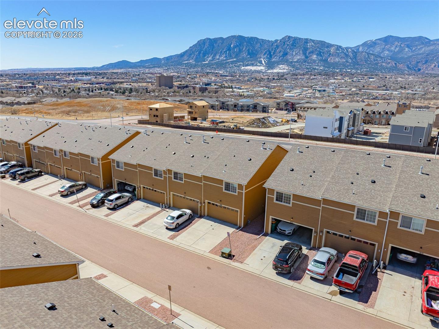 Townhome development with a mountain backdrop, featuring individual garages and asphalt shingle roofing