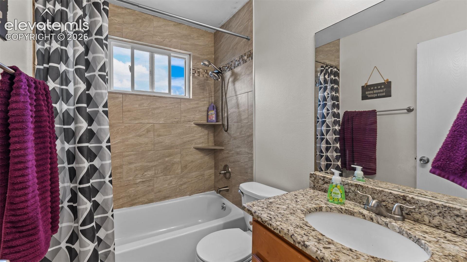 Bathroom featuring a stone-patterned vanity countertop, integrated oval basin, tiled shower surround, built-in shelving, and a large wall-mounted mirror