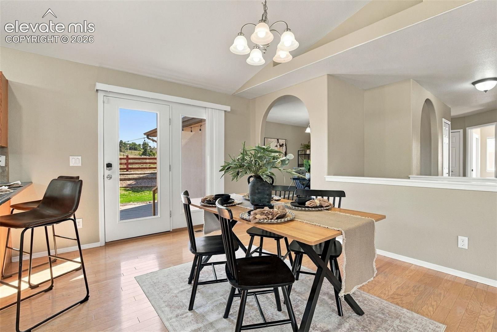 Hardwood-style flooring, arched doorways, a built-in half wall with cap, and a ceiling-mounted chandelier