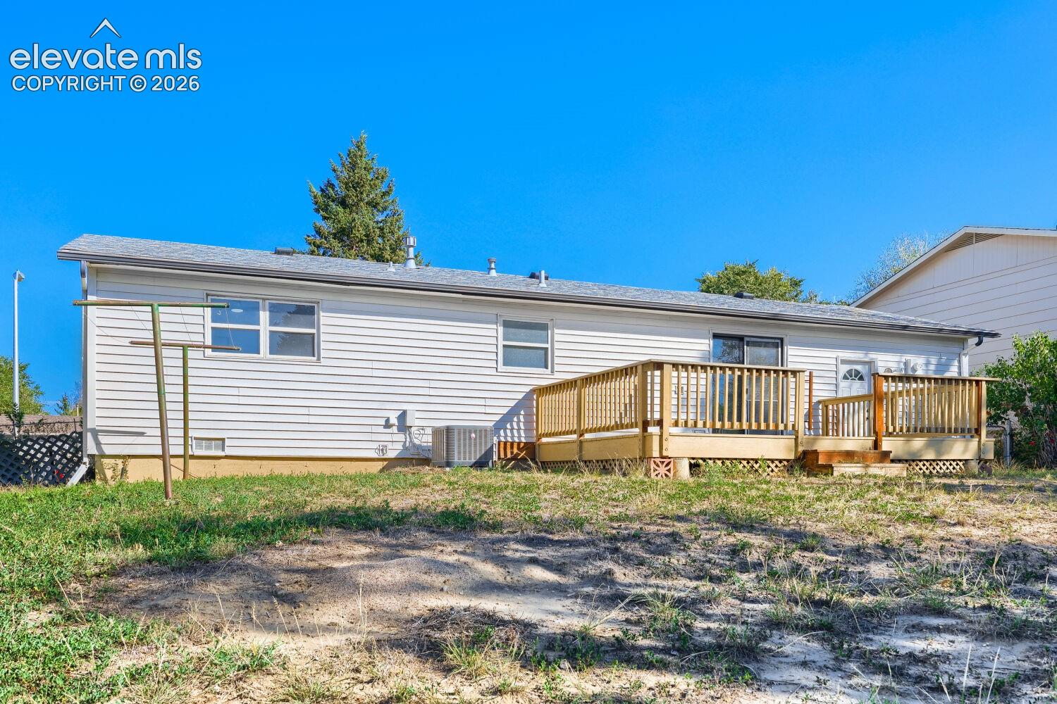Rear exterior with white siding, a multi-level wood deck, and a sliding glass door