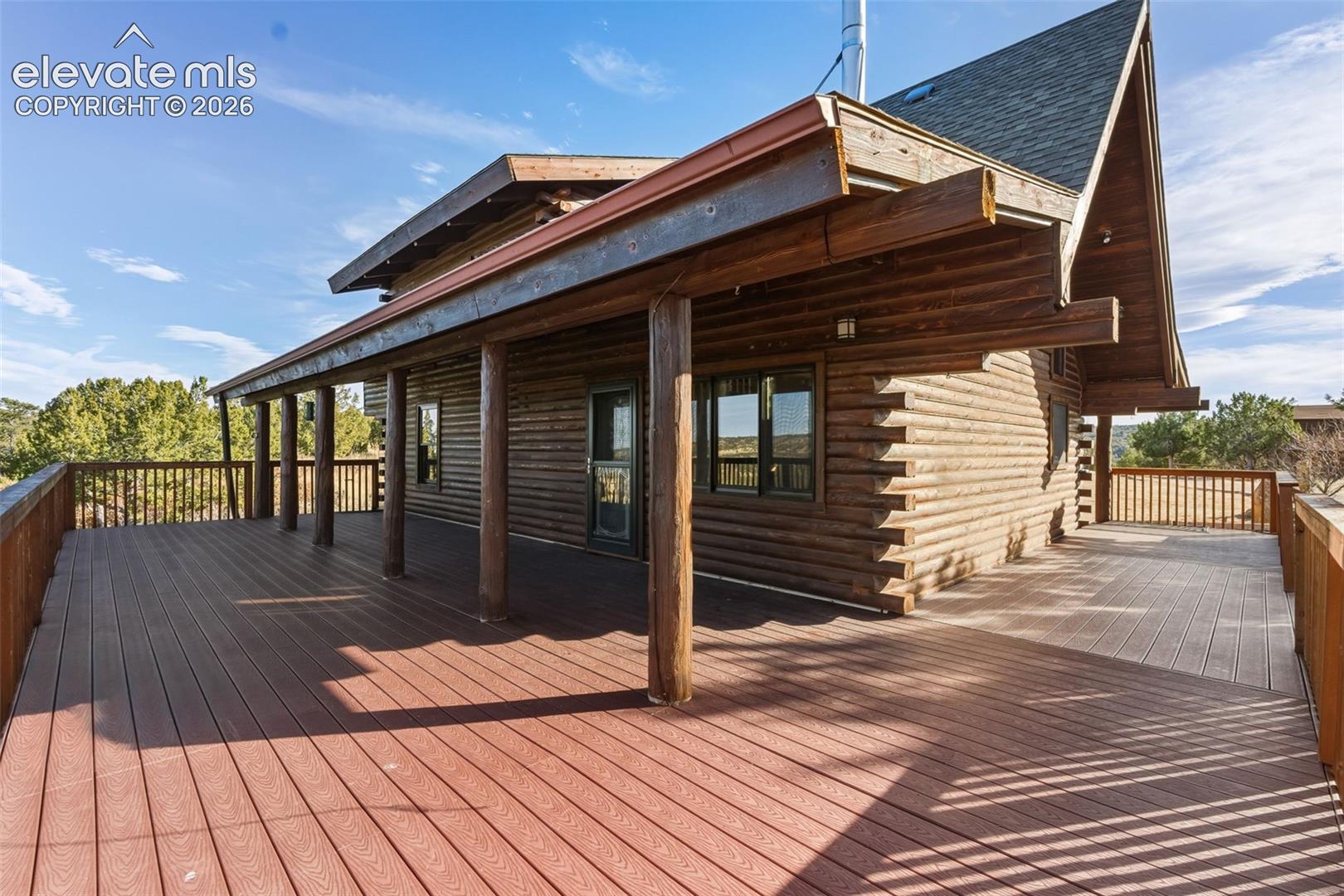 Expansive wrap-around deck featuring composite decking and a log cabin exterior