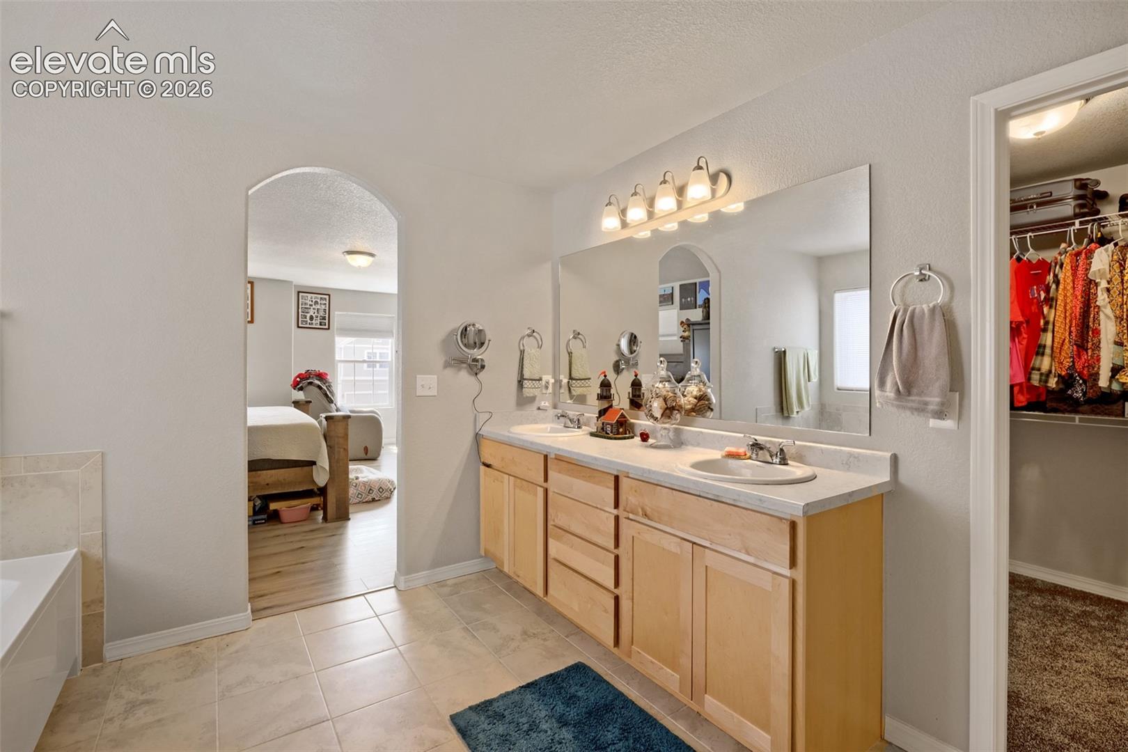 Dual vanity with light wood cabinetry and a large wall-mounted mirror
